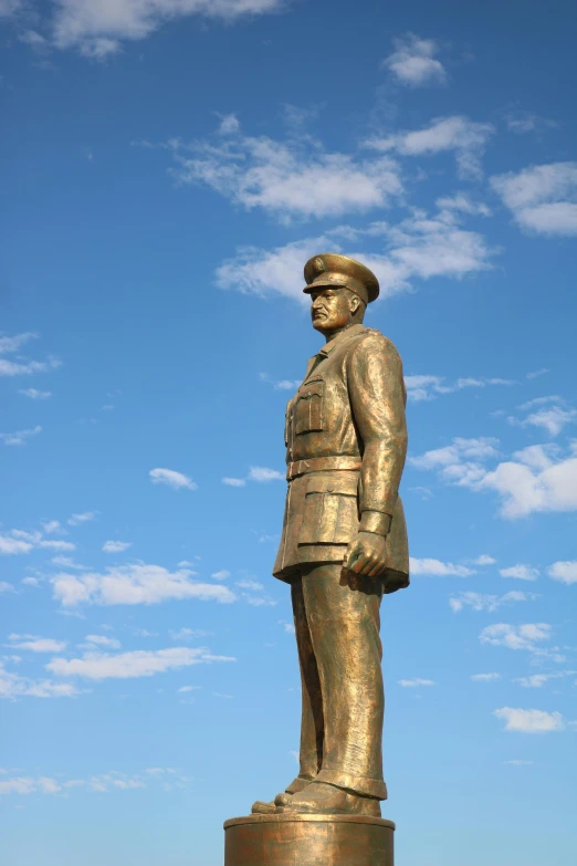 a statue of a man standing in front of a blue sky