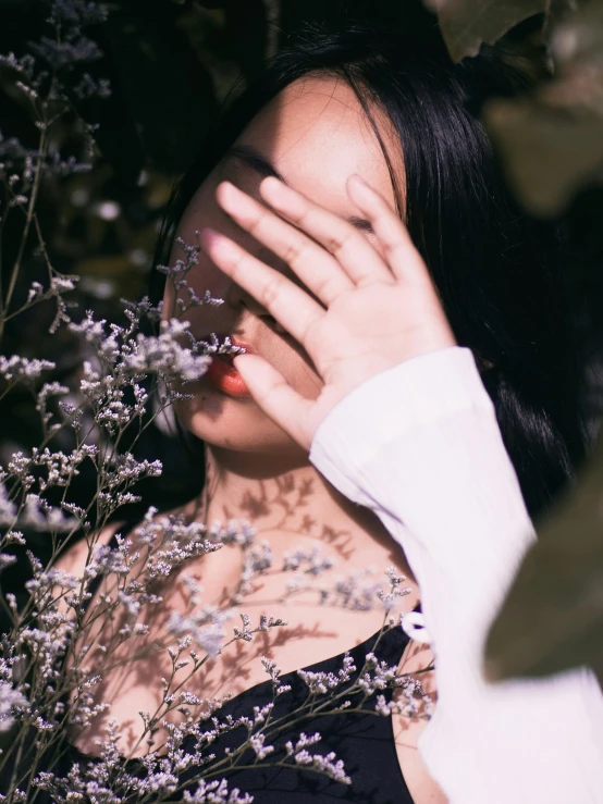 a woman covering her face behind some nches