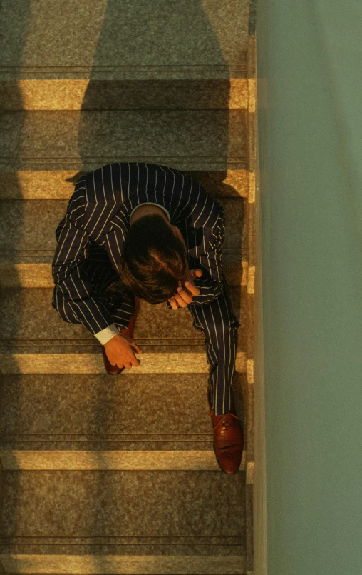 a man in a striped suit leaning against the stairs