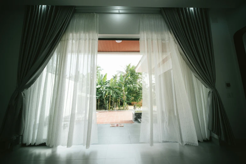 a window that has a curtain over it and plants behind it