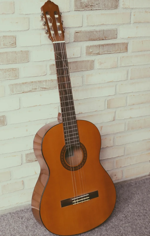 a guitar propped against a brick wall