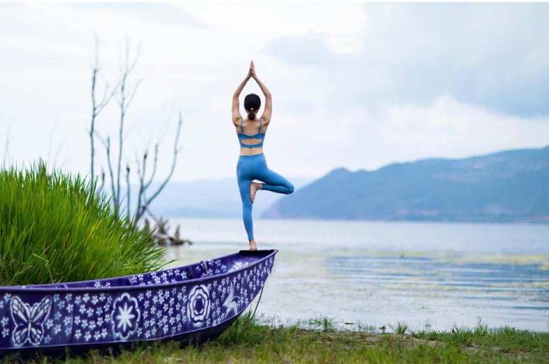 a woman doing yoga in front of a purple boat