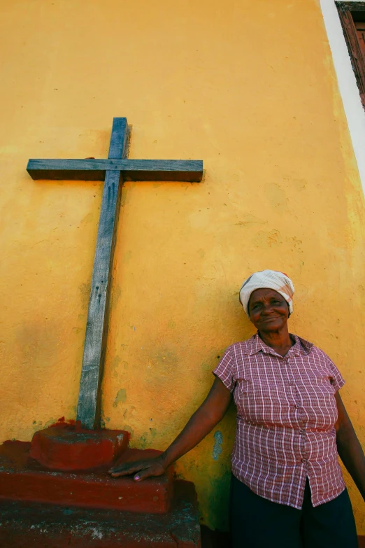 a woman standing next to a wall with a cross on it