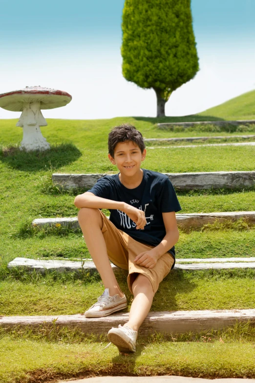 a young man sitting on a rock path in the grass