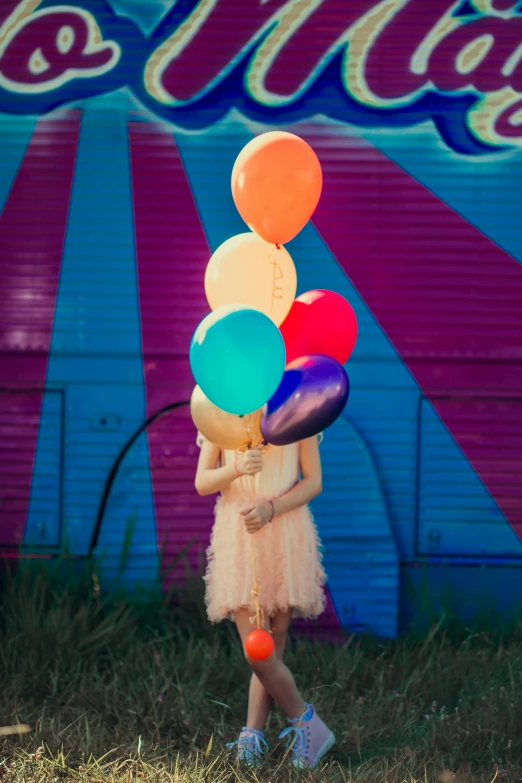a  is holding balloons against a circus wall
