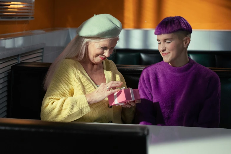 the older woman is holding a pink present in her lap