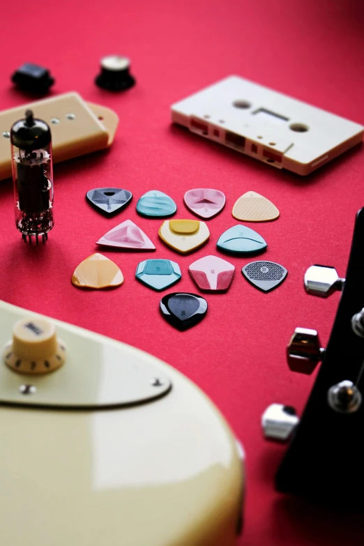 guitar picks and guitar strings lying on red surface