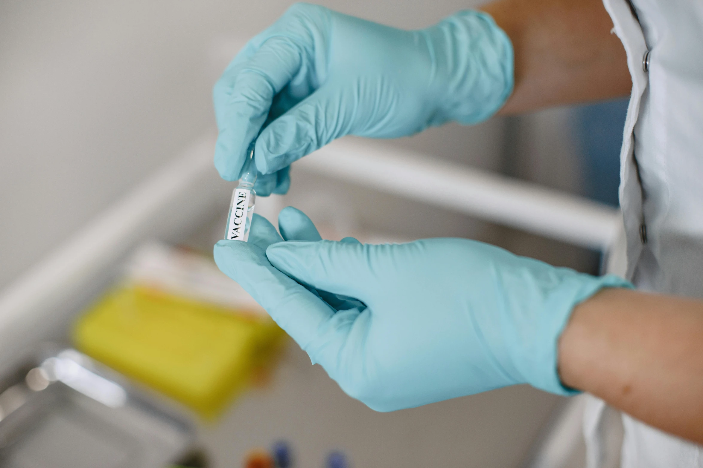 a person in blue gloves and gloves holding up some medicine