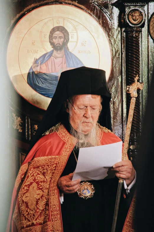 a man wearing a black clergy's hat and gown reading from a book