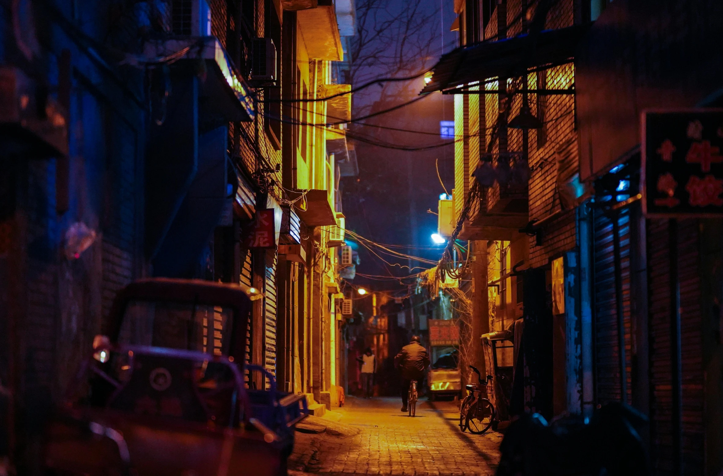 this narrow city street has neon lights on it