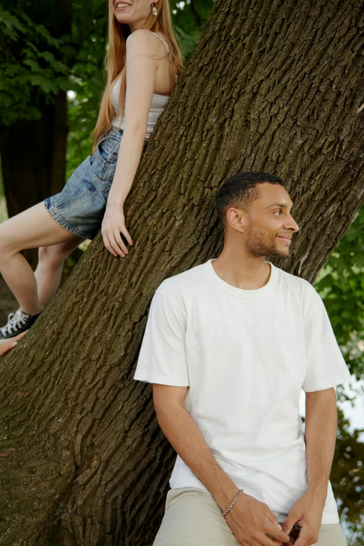 a man and woman leaning against a tree