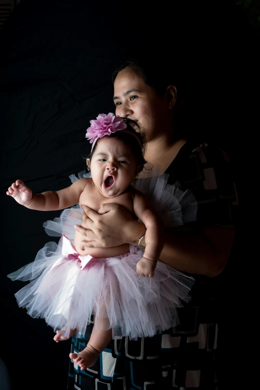 an adult holding a baby wearing a pink dress