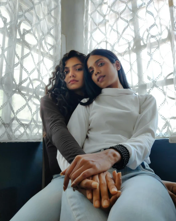 two girls are sitting on a sofa holding dogs