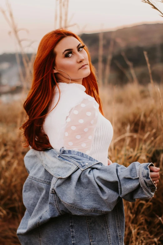 a beautiful redhead woman in a white top and denim jacket