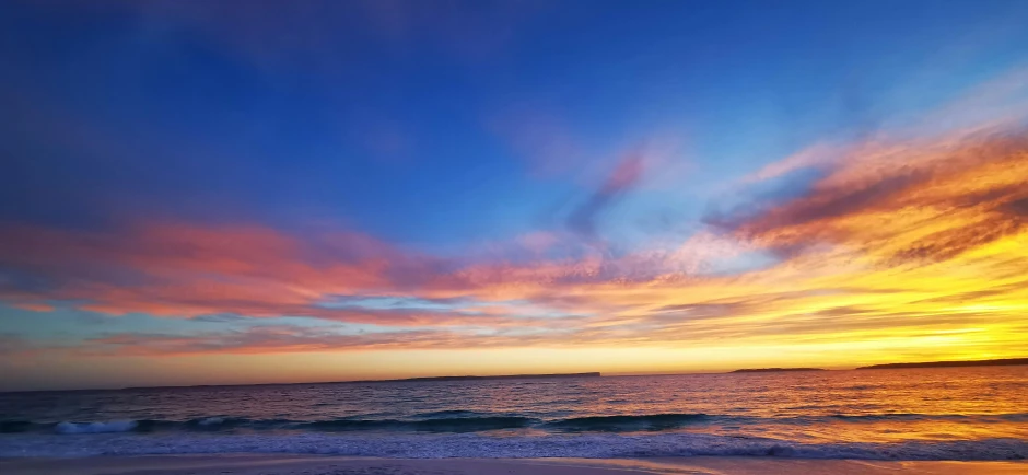 a sunset view over the ocean with colorful clouds