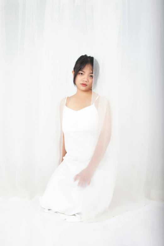 young woman in a white wedding dress posing on a sheer white background