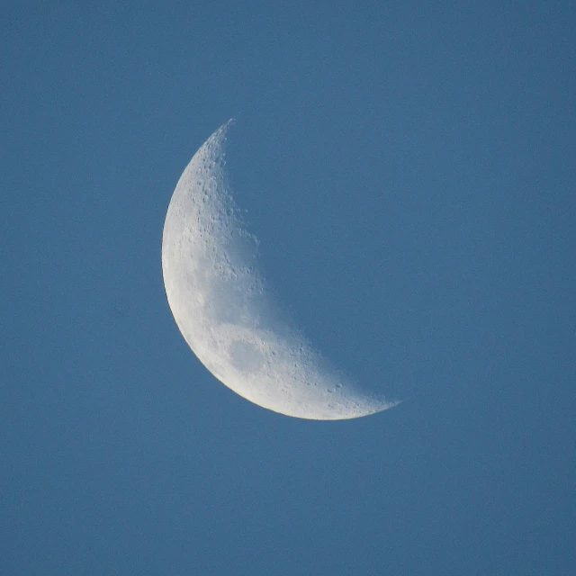 a half - moon is seen in a clear sky