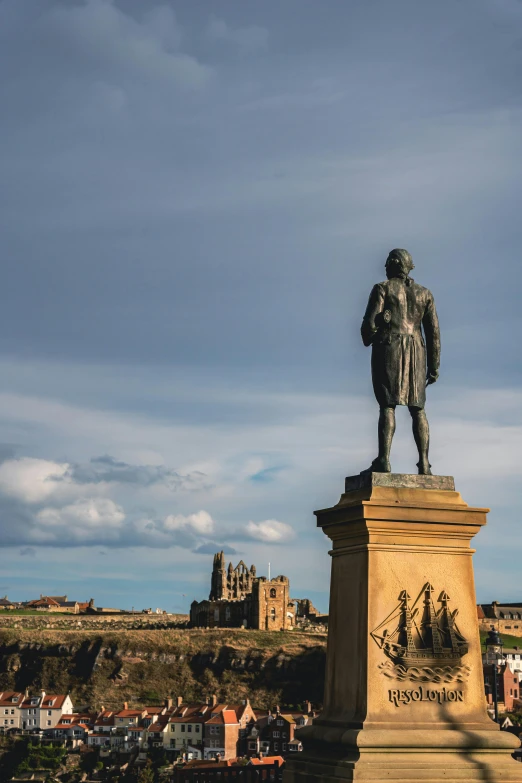 a statue is next to the castle on a hill