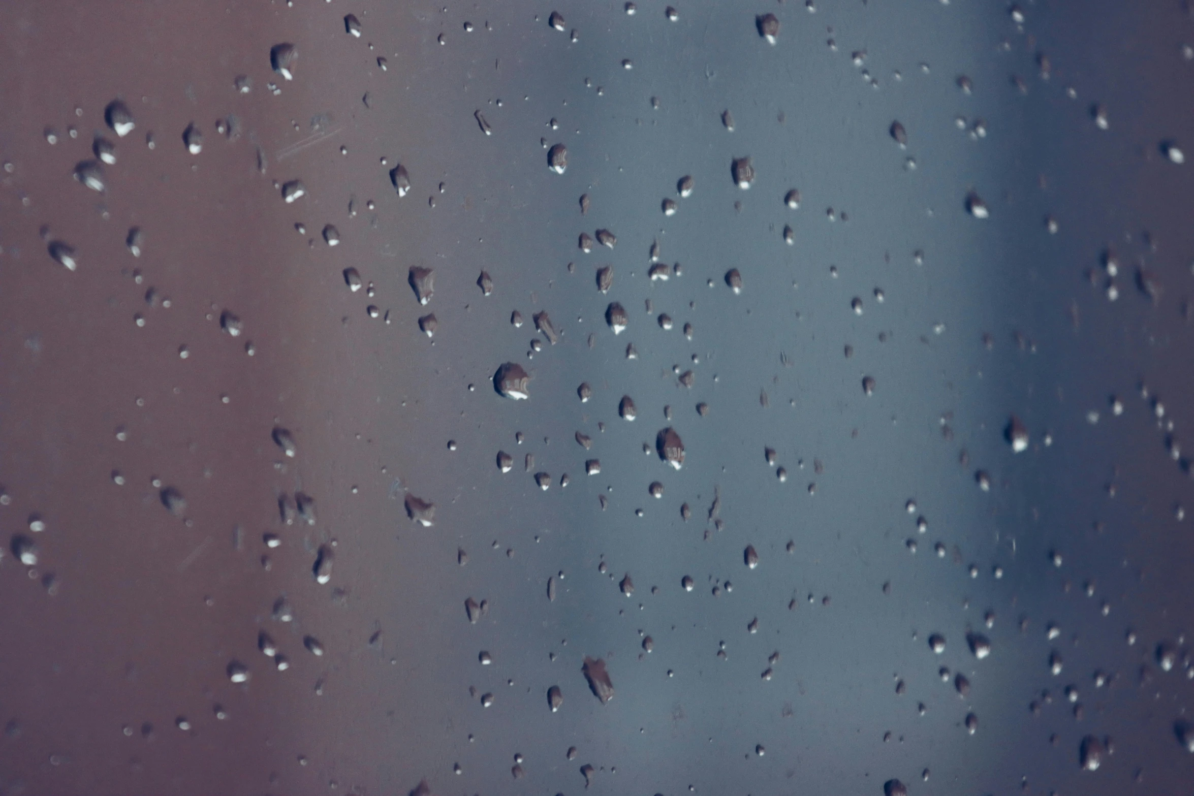 water drops on window with blue sky in background