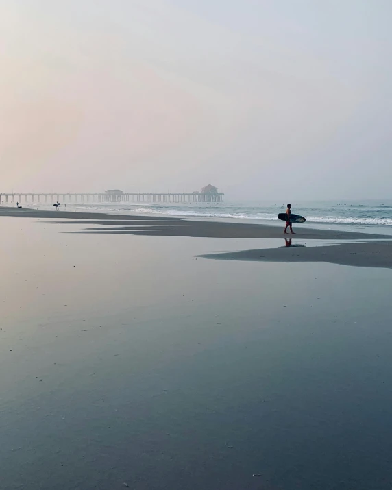 a surfer standing on the beach holding his surfboard