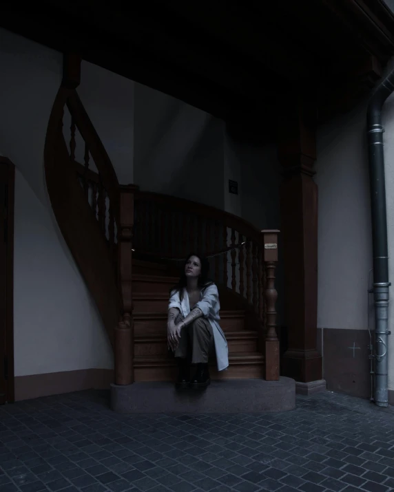 a person sitting on a stair in front of stairs