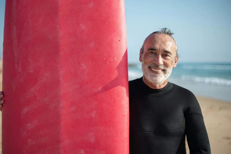 a man stands with his surfboard on a beach