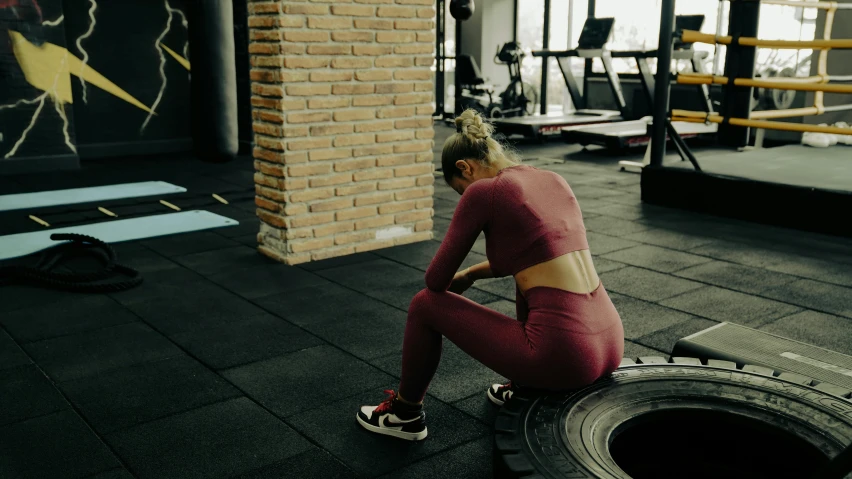 a woman sits on the floor in front of a tire