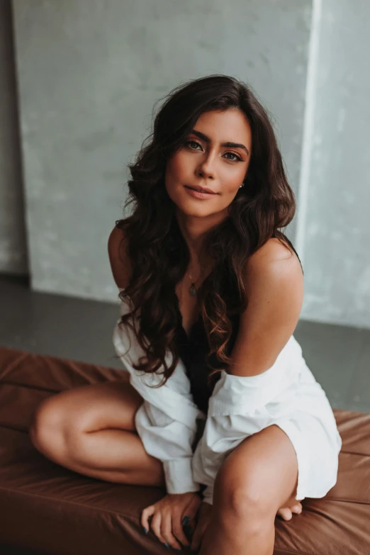 a woman in white shirt sitting on a bed