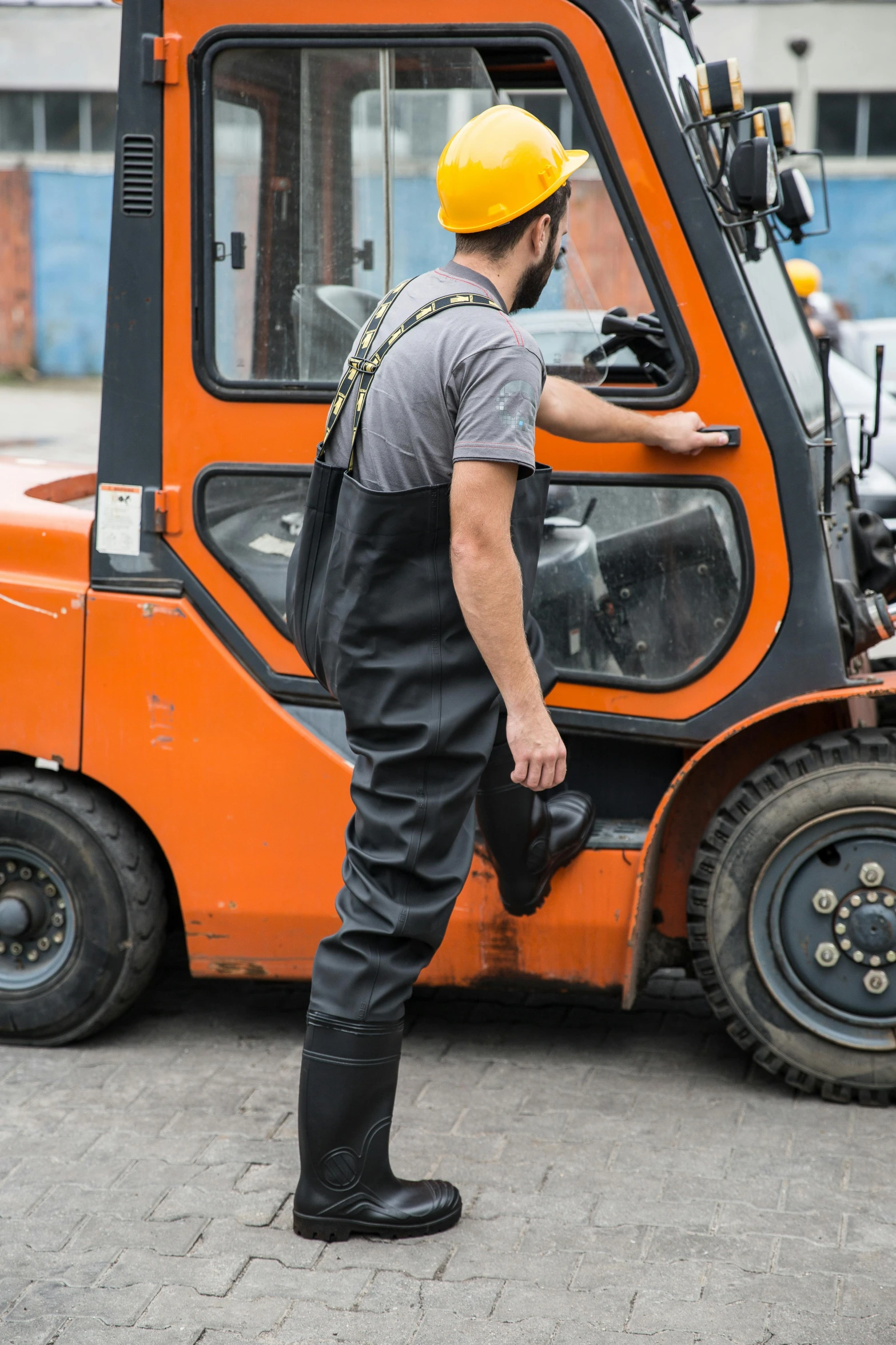 a man in an orange and black work safety outfit wearing black boots