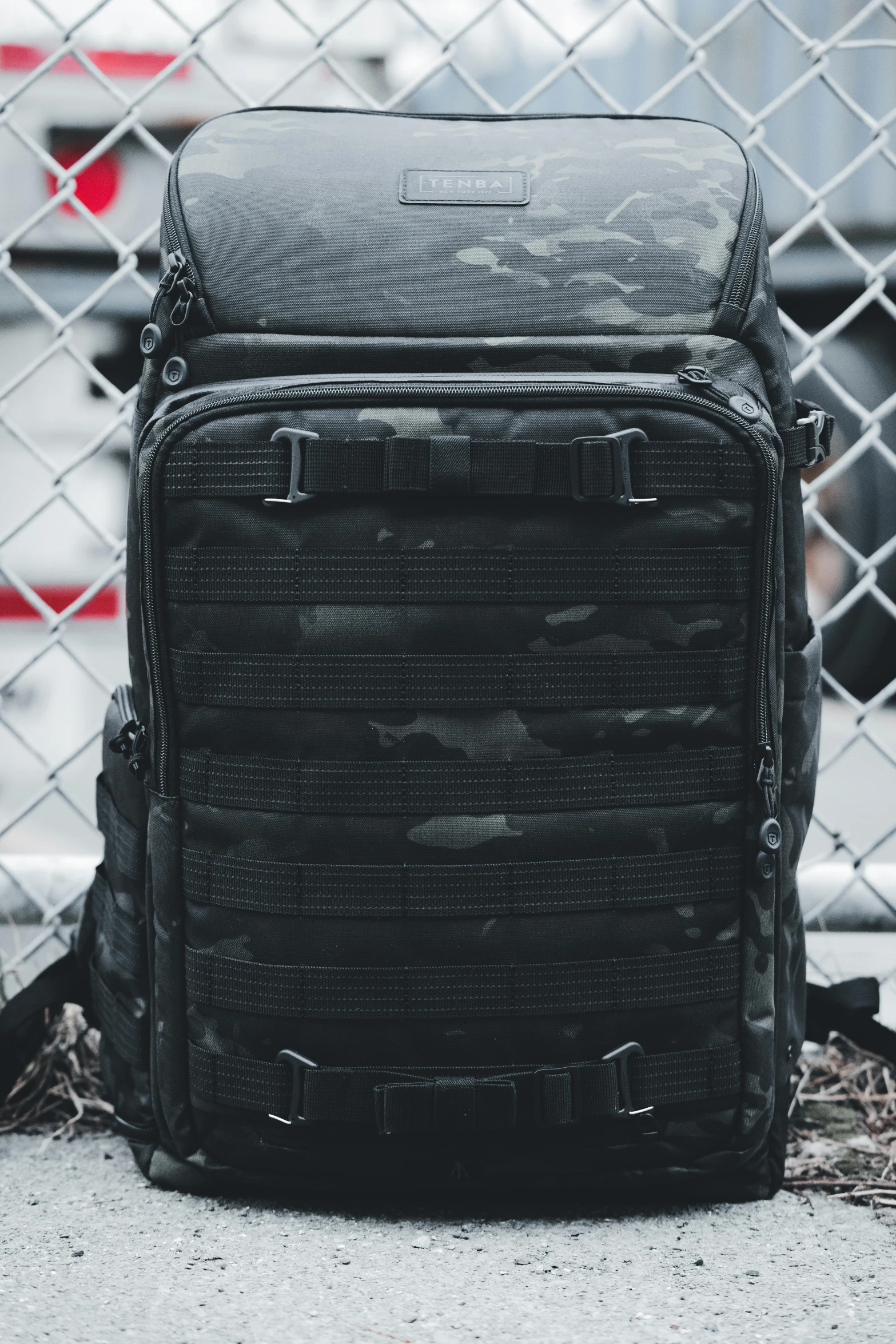 a backpack sitting in front of a chain link fence