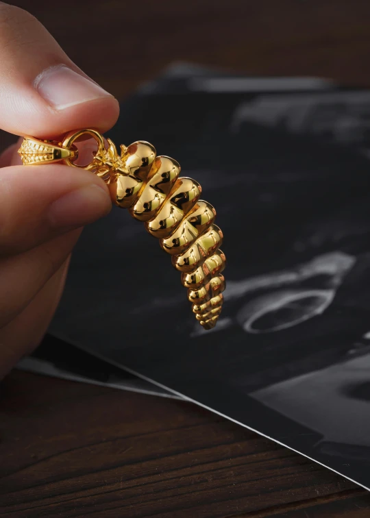 a person holding onto a gold celet on a black piece of paper