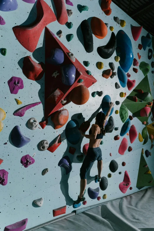 a woman is climbing on the wall with climbing equipment