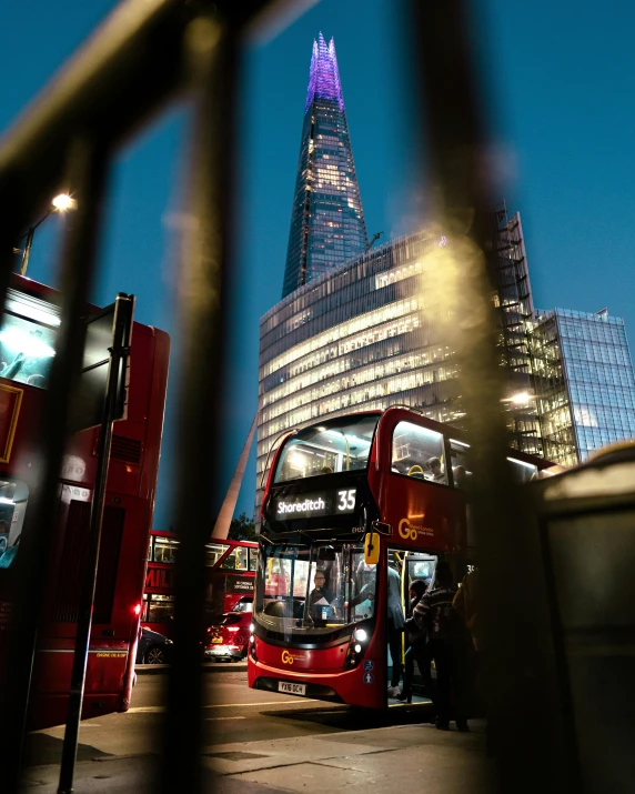 two red double decker buses parked in front of skyscrs