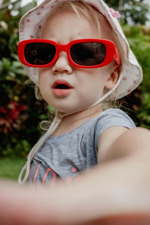 a small child with a red pair of sunglasses on