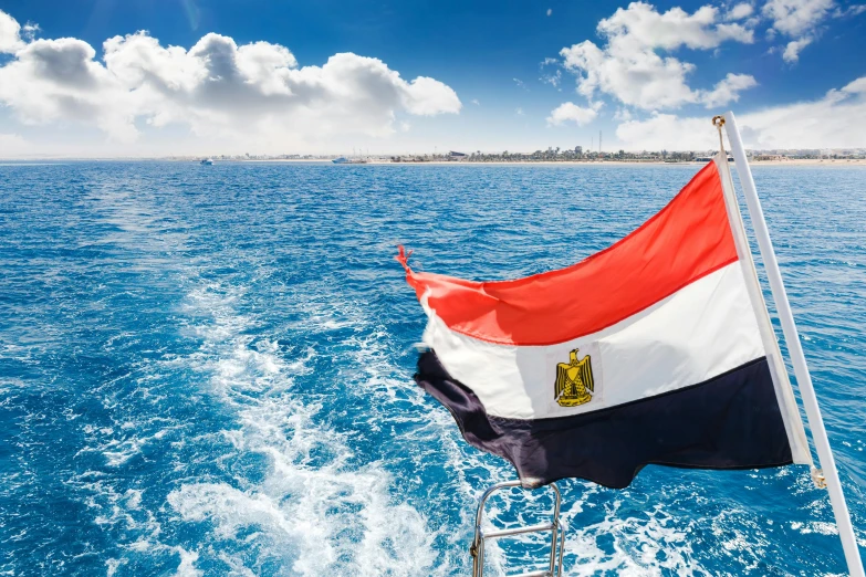 a boat sails close to a flag on a boat