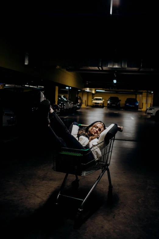 a woman laying in a shopping cart at the airport