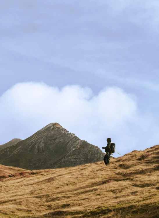 a person standing on top of a brown grass covered hillside