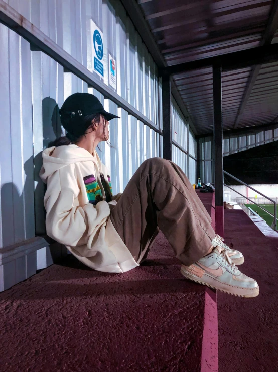 man sitting on the floor wearing sneakers and jacket