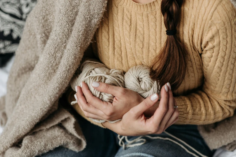 the girl is holding a ball of yarn in her hands