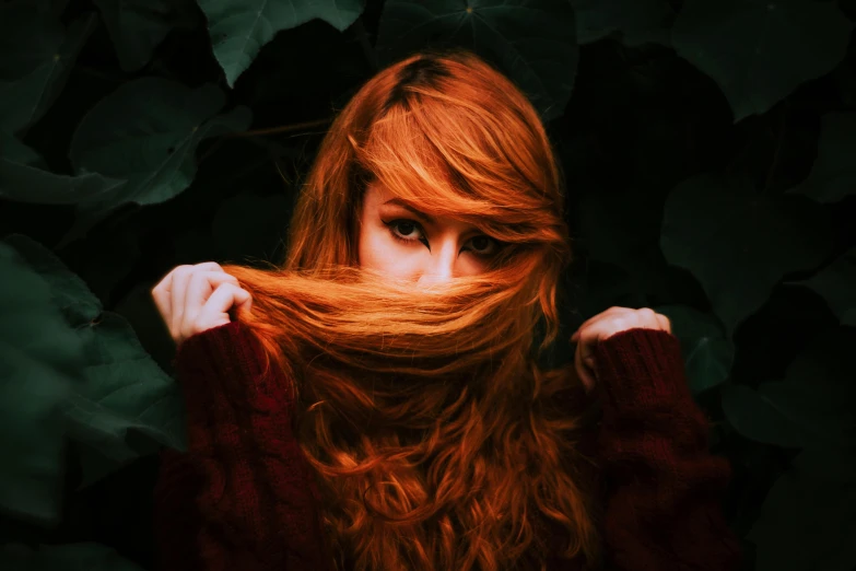 woman with red hair is standing near leaves