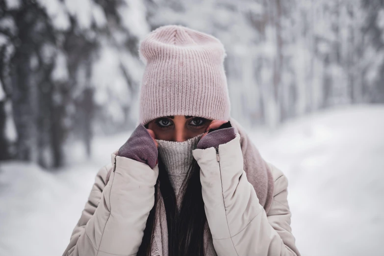 woman wearing pink winter coat and matching scarf covering her face and head