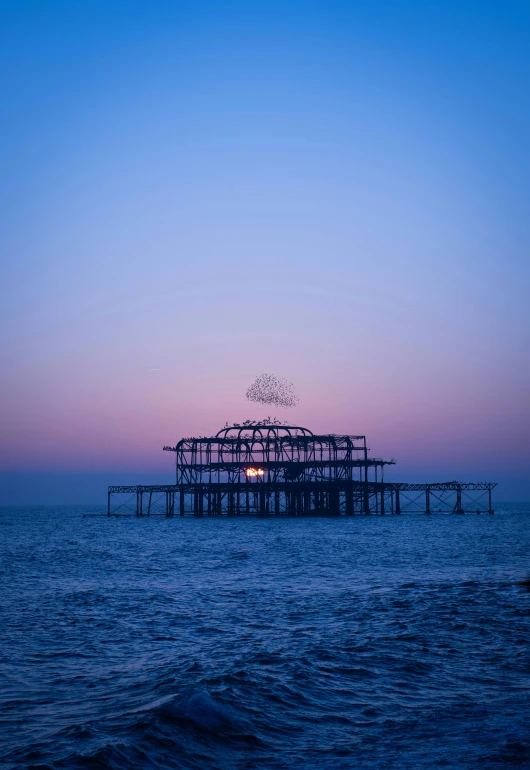 a pier on the shore with a sunset in the background