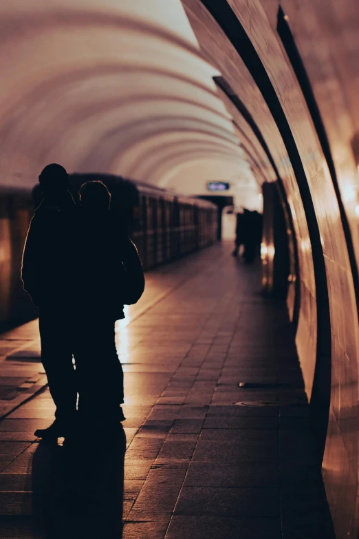 two people standing on a train platform with their arms around each other