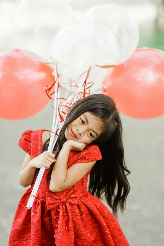 a girl holding some balloons on a street