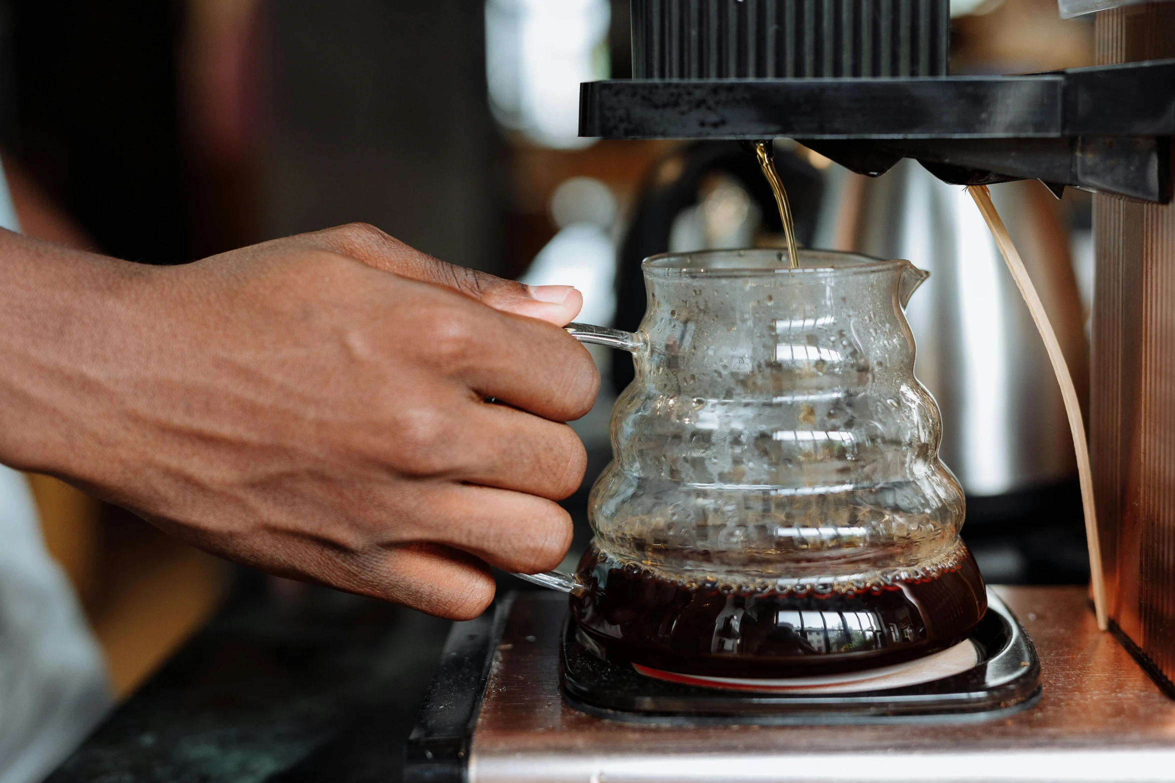 a person's hand being used to pour coffee into a cup