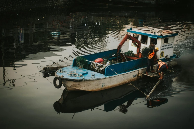 two people stand on the dock next to a blue and white boat