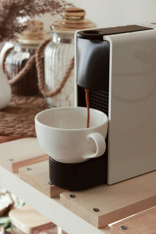 a coffee cup being filled with milk in front of a toaster