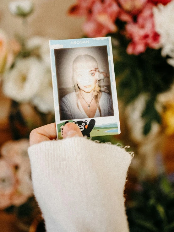 a hand is holding a picture of an old woman