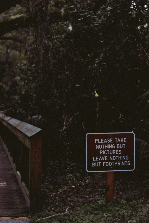 there is a sign next to the path leading to the foot bridge