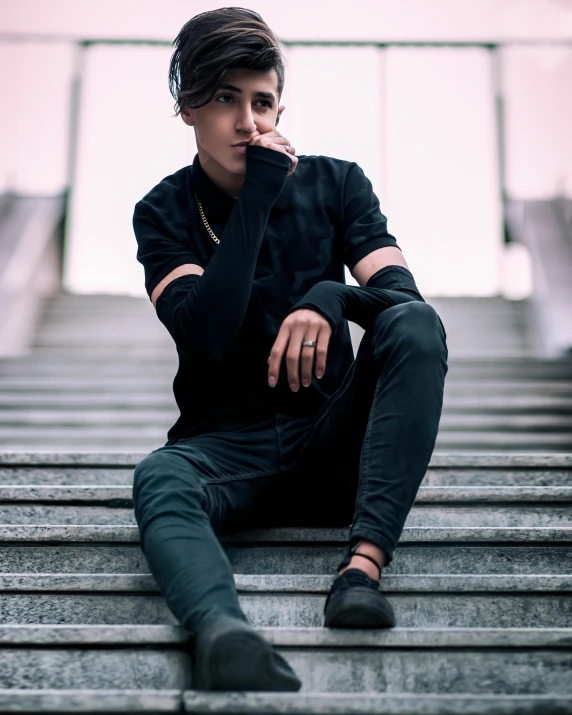 young man in black sweater sitting down on stairs with cigarette